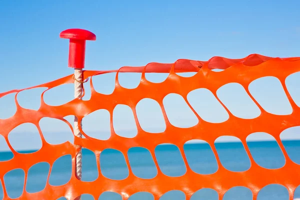 Perforated safety orange plastic grid to delimit construction site areas.