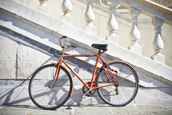 Oranje oude fiets tegen een marmeren muur (Toscane - Italië) — Stockfoto