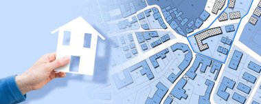 Hayali kadastro haritasına karşı satılık boş arazi. Elinde küçük bir ev olan boş arsa konsepti.