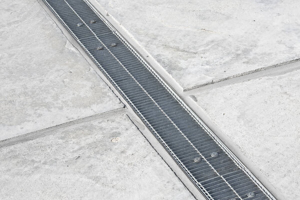 GALVANIZED INDUSTRIAL STEEL RAINWATER COLLECTION GRATE in a parking lot with concrete flooring - Drainage channel on concrete surface