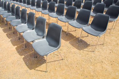 Açık hava sineması, çakıl zeminde siyah plastik sandalyeler.