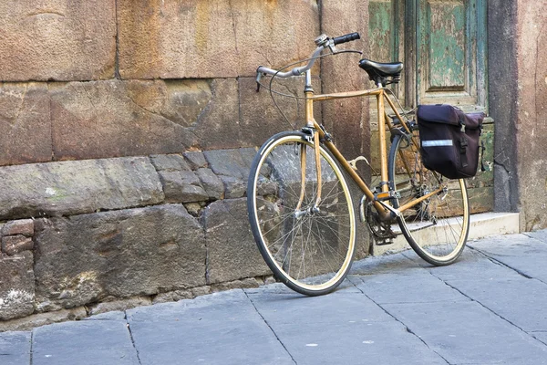 Bicicleta amarilla con bolsa contra una pared de piedra — Foto de Stock