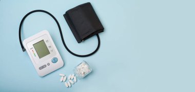 Basıncı ölçen bir cihaz, mavi tıbbi geçmişi olan bir tonometre ve birkaç beyaz hap. Baş ağrısı, hipertansiyon tedavisi ve tansiyon. Terapistin ofisi. Anlaşıldı. Pankart.