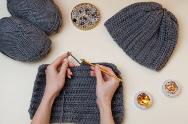 Crochet with your own hands.Knitting threads in gray.Knitting a scarf and a sweater.Female hands hold a crochet hook and knit.DIY.Knitting rules.Creativity lessons.Winter activities during quarantine