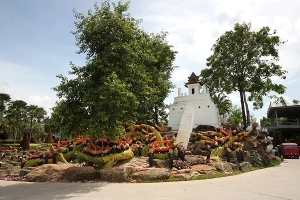 Луг с енотами, травой, деревьями и камнями в тропическом ботаническом саду Нонг Нуч недалеко от города Паттайя в Таиланде — стоковое фото