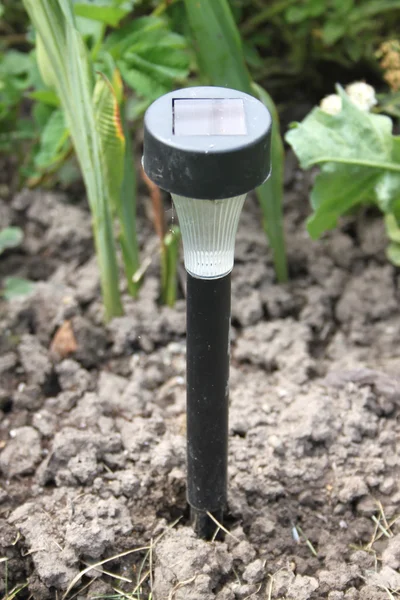 Een kleine lamp met solar batterij op een grond in de tuin van een datsja — Stockfoto