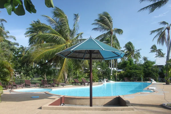 Slunečník u bazénu s jasně modrou vodou a palmy v blízkosti hotelu na ostrově koh samui v Thajsku Stock Snímky