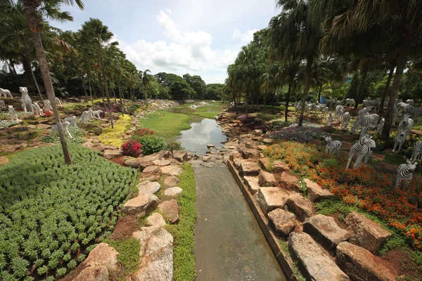 Une belle vue sur une prairie avec étang et herbe et arbres et pierres dans le jardin botanique tropical Nong Nooch près de la ville de Pattaya en Thaïlande — Photo