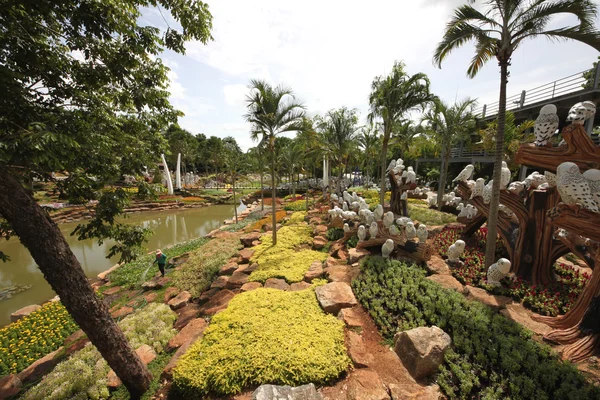 Une prairie avec hibou et herbe et arbres et pierres et étang dans le jardin botanique tropical Nong Nooch près de la ville de Pattaya en Thaïlande — Photo