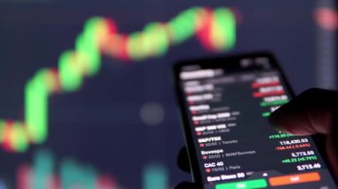 Akıllı telefon ve bilgisayar ekranında finans piyasasında bilgi izleyen adam