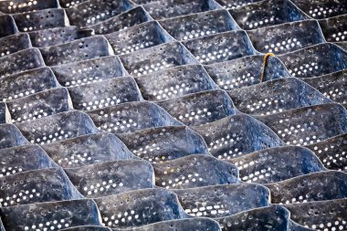 Cellular confinement system - plastic black honeycomb frame filled with small natural stones closeup. Used in construction for erosion control, soil stabilization on flat ground and steep slopes clipart