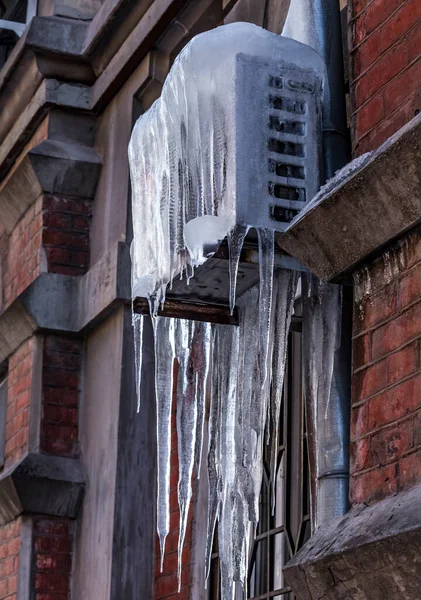 Air conditioner covered with ice and icicles. Aged old house wall. Cold cooling concept. ?roblem with air conditioning in winter