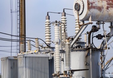 Transformatör petrol tankının yüksek voltajlı antika elektrik santralini kapatın. Elektrik santralinin kabloları, bağlantıları ve izolatörlerine yakın çekim.