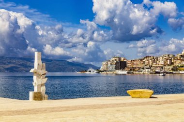 Saranda, Arnavutluk - 14 Mayıs 2021: Yeni çağdaş kent setinden şehir limanı ve kasaba manzarası. Modern heykeller seti süslüyor. Güneşli bir yaz günü. Korfu adası ufukta görünüyor..