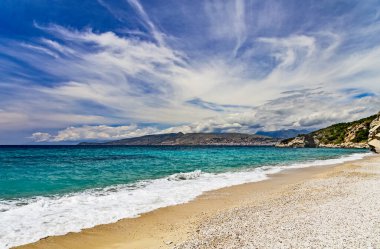 Albania, Saranda resort. View of the rocks, beach and the sea, Corfu island is on the horisont. Blue sea and sky with white clouds. Ionian Sea