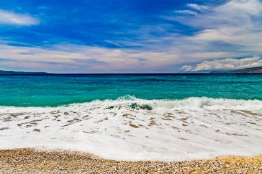 Albania, Saranda resort. View of the rocks, beach and the sea, Corfu island is on the horisont. Blue sea and sky with white clouds. Ionian Sea
