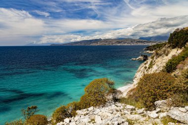 Albania, Saranda resort. View of the rocks, beach and the sea, Corfu island is on the horisont. Blue sea and sky with white clouds. Ionian Sea