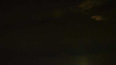 Geceleyin bulutların arkasında yükselen dolunay.