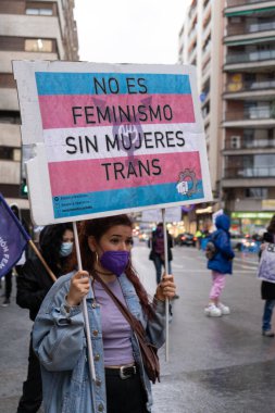 Kadın, kadın hakları için bir protesto posteri tutuyor. Yağmur yağarken ortaya çıkan bir tezahürat.