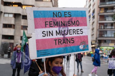 Kadın, kadın hakları için bir protesto posteri tutuyor. Yağmur yağarken ortaya çıkan bir tezahürat.