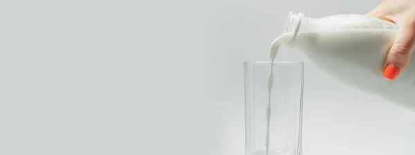 Dose diária de leite. Tiro de derramamento, espirrando leite fresco em um copo transparente contra fundo branco. Conceito de produto lácteo. Copo de enchimento com leite de perto. — Fotografia de Stock