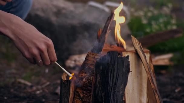年轻的旅行者在森林里点燃着篝火，在大自然中燃起了一根长长的火柴。手拿着结婚戒指靠得很近露营。在山上远足。旅游。旅行 — 图库视频影像