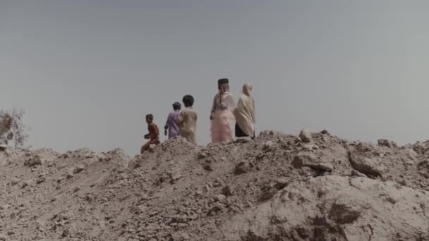 Five children of slaves walk through the territory of a brick factory in Pakistan. Kids in labour slavery. Slow Motion. Karachi, Pakistan - September, 2021 — Stock Video