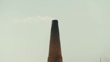 Pakistan 'da köle işçi çalıştıran bir tuğla fabrikası. Mirpur Khas. Kumda boş bir karavan var. Arka planda duman olan büyük tuğla pipo. Yavaş çekim