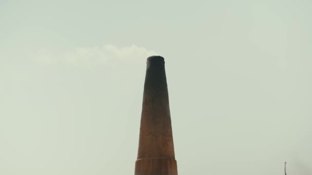 Цегляна фабрика в Пакистані, яка використовує рабську працю. Мірпур Кхас. На піску є порожній трейлер. Велика цегляна труба з димом на задньому плані. Повільний рух — стокове відео