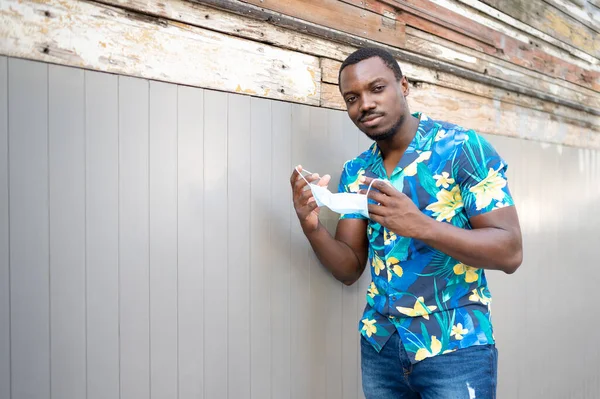 Covid-19 salgınında maskeli genç bir zenci korunmak için. Afro-Amerikalı bir adam yüz maskesi takıyor. Cep telefonlu Afro-Amerikalı adam..