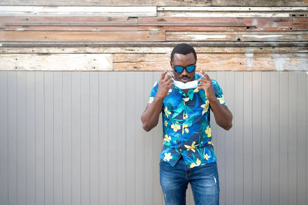 Covid-19 salgınında maskeli genç bir zenci korunmak için. Afro-Amerikalı bir adam yüz maskesi takıyor. Cep telefonlu Afro-Amerikalı adam..