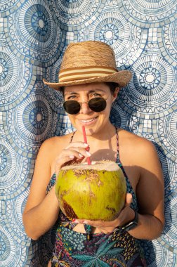 Mutlu kadın havuzda dinleniyor ve hindistan cevizi suyu içiyor. Açık havuzda gülümseyen sevimli bir kadının portresi. Tropik bir havuzda gezgin kavramı. Açık hava yaşam tarzı.