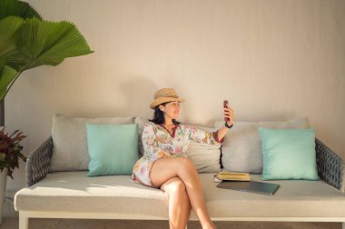 Evinin bahçesinde dizüstü bilgisayarda çalışan gülümseyen bir kadın. Evden çalışma kavramı. Evden sosyal uzaklık. Çalışma Ofisi.