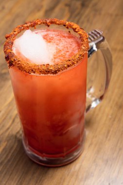Michelada birası ve domates suyu. Tahta masada biralı Clamato. Meksika içki konsepti