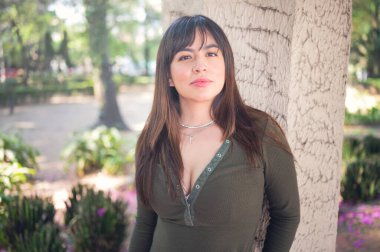 Yaz ikliminde parkta rahat ve mutlu bir kadın. Açık havada gülümseyen güzel bir kadının portresi. Açık hava yaşam tarzı kavramı. Latin kız gücü. Meksikalı kız