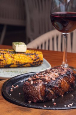 Ahşap masada ızgara biftek ve sarımsaklı mısır. Meksika yemeği.