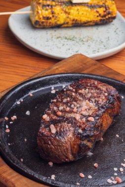 Ahşap masada ızgara biftek ve sarımsaklı mısır. Meksika yemeği.