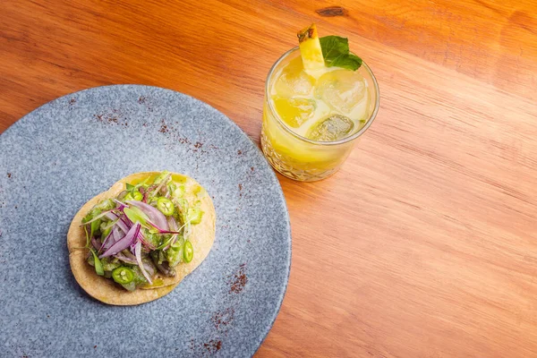 Meksika usulü, yeşil biberli taco ve mermer tabakta mor soğan. Meksika usulü taco ve sarı kokteyl.