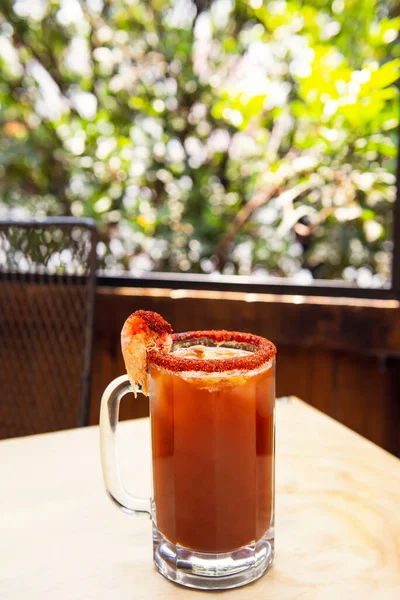 Michelada birası ve domates suyu. Tahta masada biralı Clamato. Meksika içkisi. Domates suyu, karides, midye ve limon ile Michelada birası, Meksika 'da Meksika içkisi. Meksika birası kavramı.