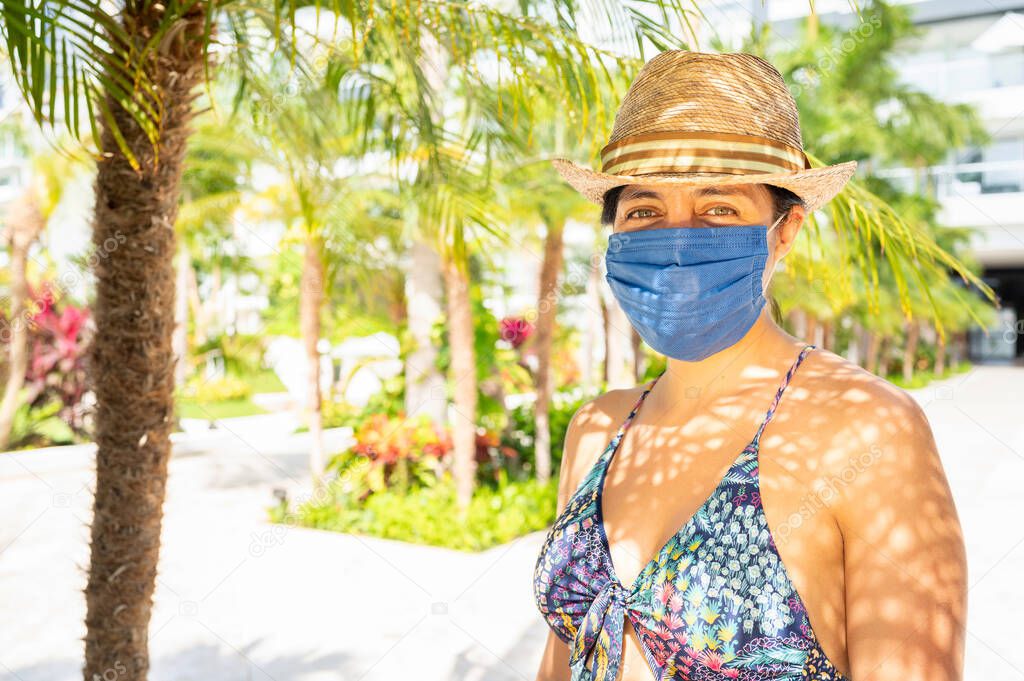 Young man with medical mask in tropical climate, new normal concept. Life in the coronavirus pandemic, travel and vacations at sea