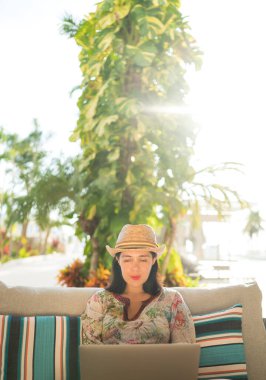 Evinin bahçesinde dizüstü bilgisayarda çalışan gülümseyen bir kadın. Evden çalışma kavramı. Evden sosyal uzaklık. Çalışma Ofisi