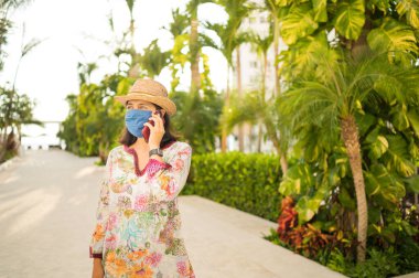 Evinin arka bahçesinde telefonla konuşan gülümseyen genç bir kadın. Evden çalışma kavramı. Evden sosyal uzaklık