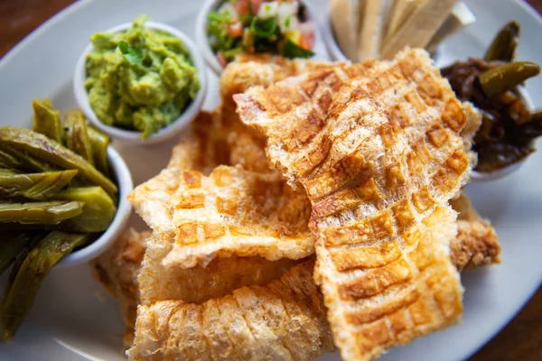 Mexican Pork rind. Nopales and guacamole. Mexican food on wooden background. Traditional Mexican food concept. Mexican chicharron.