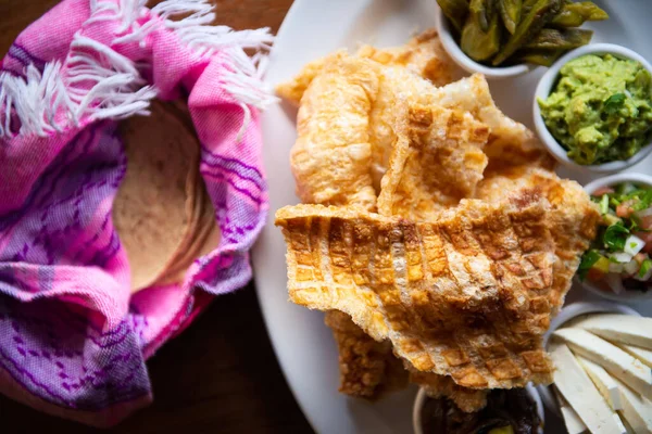 墨西哥猪肉皮 Nopales和Guacamole 墨西哥食物的木制背景 墨西哥传统食品的概念 墨西哥奇卡龙 免版税图库图片