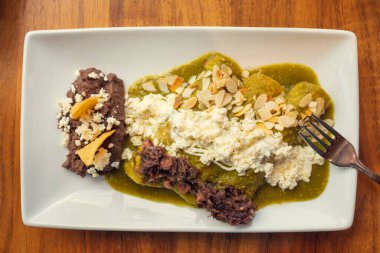 Fasulyeli yeşil enchilada. Fasulyeli geleneksel Meksika yemeği. Geleneksel Meksika gurme yemek konsepti, geleneksel yeşil enchilada