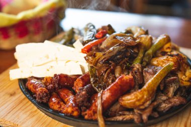 Hakiki Meksika barbeküsü, restoran masasında kızartılmış farklı kesikler. Chistorra, et ve ızgara peynir. Meksika bifteği konsepti.