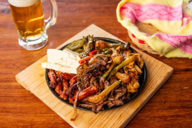Hakiki Meksika barbeküsü, restoran masasında kızartılmış farklı kesikler. Chistorra, et ve ızgara peynir. Meksika bifteği konsepti.