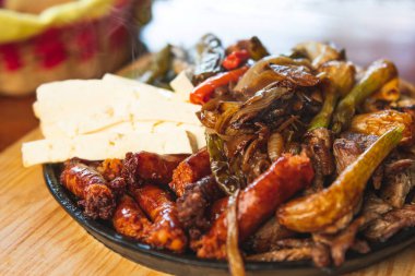 Hakiki Meksika barbeküsü, restoran masasında kızartılmış farklı kesikler. Chistorra, et ve ızgara peynir. Meksika bifteği konsepti.