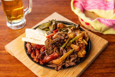 Hakiki Meksika barbeküsü, restoran masasında kızartılmış farklı kesikler. Chistorra, et ve ızgara peynir. Meksika bifteği konsepti.