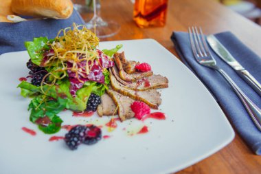 Öğle yemeğinde restoran menüsünde sebzeli ördek göğsü ve meyve. Salatalı gurme ördek.